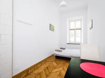 a white room with a bed and a red rug at CASIO in Kraków