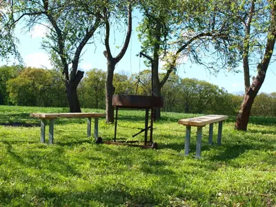 two benches and a chair in a field with trees at Panorama Racławicka Domek Willa Basen Agroturystyka in Janowiczki