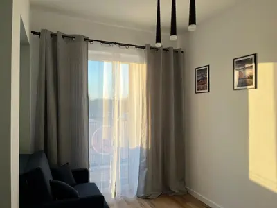 a living room with a window with curtains and a chair at Apartament Marko Due in Zator