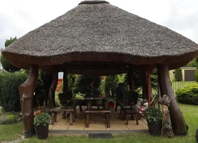 a large straw roofed gazebo with chairs and a table at Agrostrzecha in Ryczów