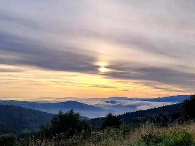 a sunset in the mountains with clouds and trees at Domek na Kleninie z gorącą balią in Kamienica