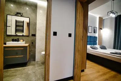 a bathroom with a bed and a sink and a mirror at Apartament No 61 Blue Holiday Home Zator in Zator