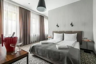 a hotel room with a bed and a table and windows at No.23 Premium Aparthotel in Kraków