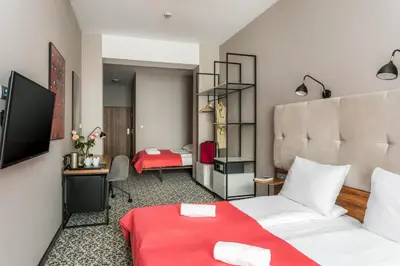 a hotel room with a white bed and a red blanket at No.23 Premium Aparthotel in Kraków