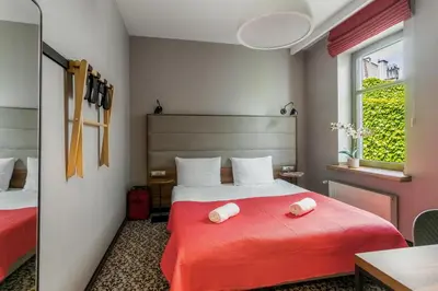 a bedroom with a red bed with two towels on it at No.23 Premium Aparthotel in Kraków