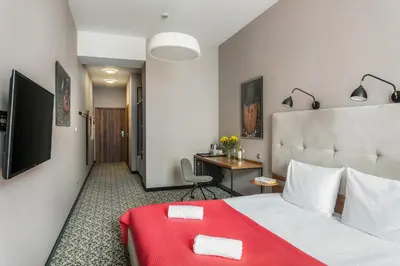 a hotel room with a bed with a red blanket at No.23 Premium Aparthotel in Kraków