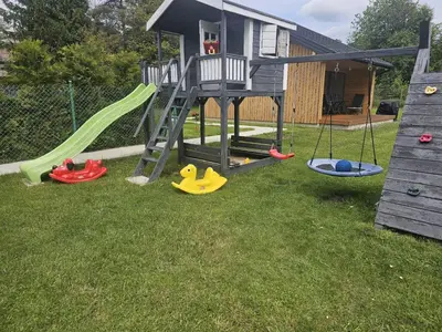 a playground with a slide and play equipment in a yard at Domek Komfort w górach przy Parku in Rabka