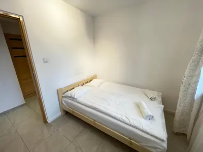 a small bedroom with a bed with white sheets at Apartament Park Zakrzowek in Kraków