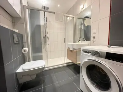 a bathroom with a washing machine and a sink at Apartament Park Zakrzowek in Kraków