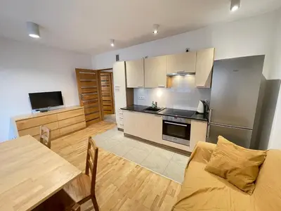 a large kitchen with a table and a refrigerator at Apartament Park Zakrzowek in Kraków