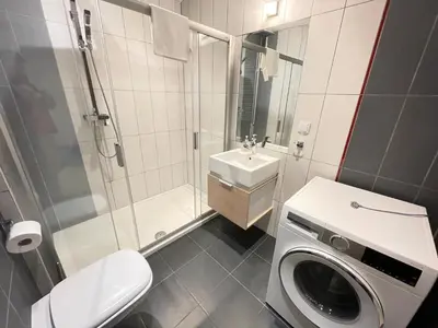 a bathroom with a washing machine and a sink at Apartament Park Zakrzowek in Kraków