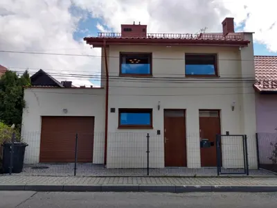 a white house with brown doors and a fence at Włodarska 11 in Kraków