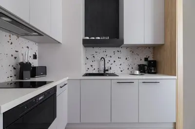 a white kitchen with white cabinets and black appliances at Casa Feliz Zabłocie Studio for 4 Guests Cracow by Noclegi Renters in Kraków