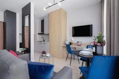 a living room with a couch and a table with blue chairs at Casa Feliz Zabłocie Studio for 4 Guests Cracow by Noclegi Renters in Kraków