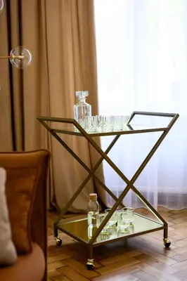 a glass serving cart with glasses and bottles on it at Native Apartments Dietla 71 in Kraków