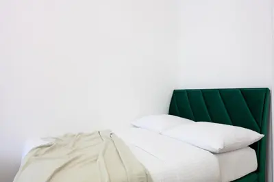 a bed with a green headboard and white pillows at Native Apartments Dietla 71 in Kraków
