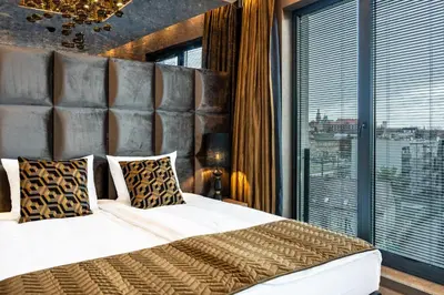 a bedroom with a large bed and a large window at Art Suites Luxury Hotel in Kraków