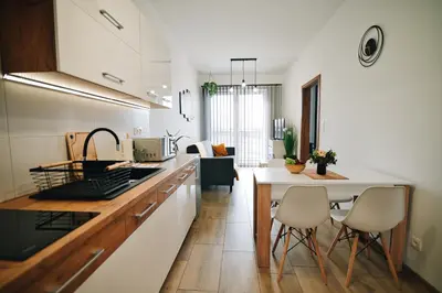 a kitchen with white cabinets and a table and chairs at Apartament 30tka by Housine in Zator