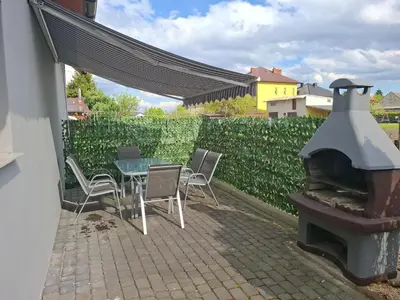 a patio with a table and chairs and a fireplace at Mieszkanie B Łowiczki in Zator