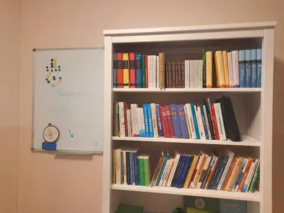 a book shelf filled with books next to a white board at Karmelitański Dom Gościnny in Zawoja