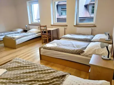 a room with three beds and a table and two windows at Karmelitański Dom Gościnny in Zawoja