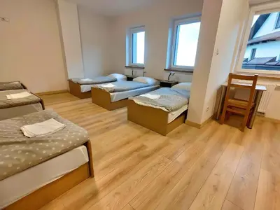 three beds in a room with wooden floors and windows at Karmelitański Dom Gościnny in Zawoja
