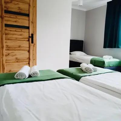 two beds in a room with white sheets and towels at Zielony Zakątek Przeciszów Zator in Przeciszów