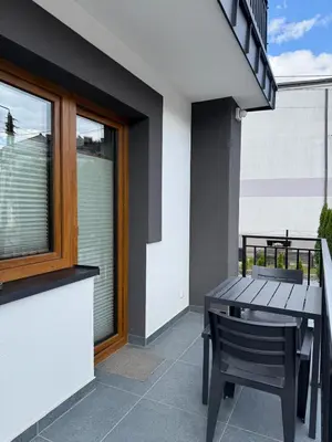 a table and chair on a balcony with a window at Apartamenty Wadowity- Energylandia Zator in Wadowice
