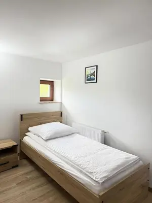 a bed in a bedroom with a white wall at Apartamenty Wadowity- Energylandia Zator in Wadowice