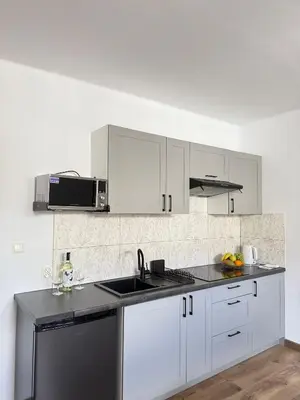 a white kitchen with white cabinets and a sink at Apartamenty Wadowity- Energylandia Zator in Wadowice
