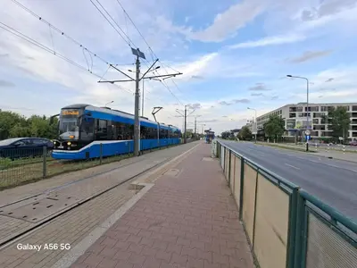 a blue train traveling down a street next to a road at Bagry Rooms3 LoveKrakow in Kraków